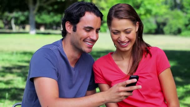 Pareja feliz mirando un texto en un teléfono móvil — Vídeo de stock