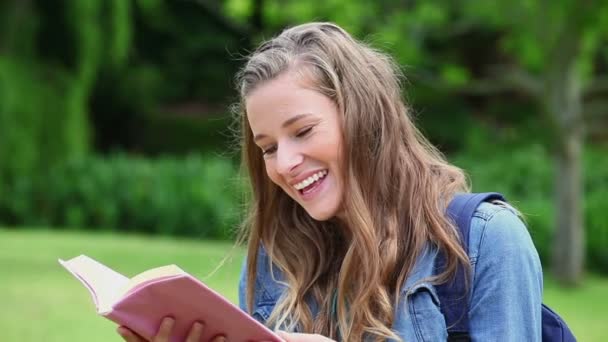 Sorrindo jovem mulher lendo um livro — Vídeo de Stock