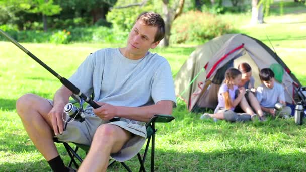 Famille souriante assis derrière le père qui pêche — Video