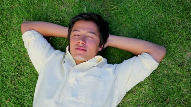 Улыбающийся человек, лежащий на траве — стоковое видео