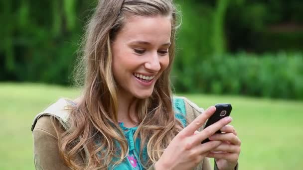 Glad ung kvinna skriver på sin mobiltelefon — Stockvideo