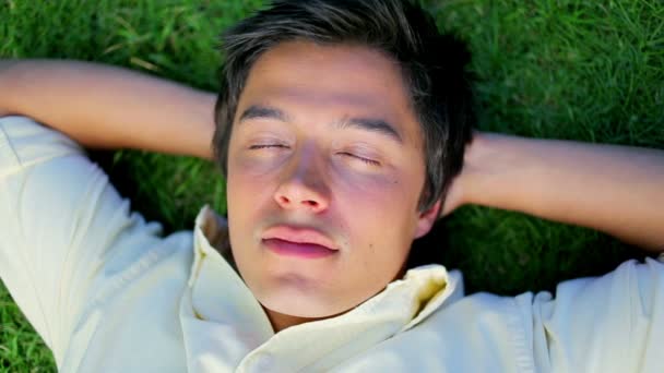 Fredlig man tupplur liggande i gräset — Stockvideo
