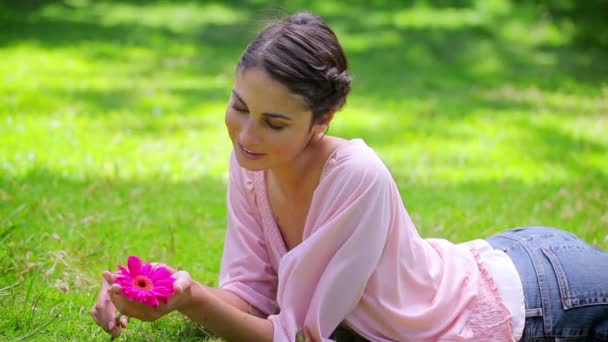 Sorridente giovane donna che tiene un fiore rosa — Video Stock