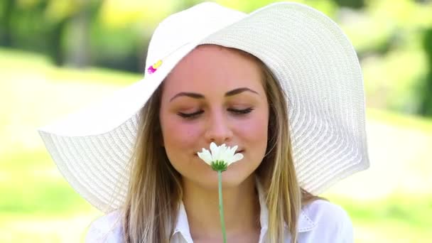 Mujer rubia sonriente sosteniendo una flor — Vídeos de Stock