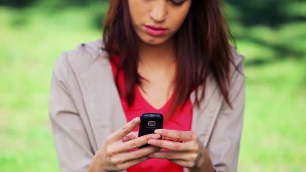 Mujer morena seria mensajes de texto en su teléfono móvil — Vídeos de Stock
