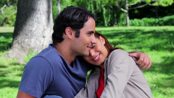 Sorrindo casal abraçando uns aos outros enquanto sentado na grama — Vídeo de Stock