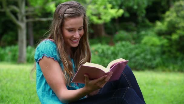 Mulher sorridente lendo um romance fascinante — Vídeo de Stock