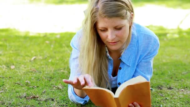 Mujer leyendo mientras está acostada en frente — Vídeos de Stock
