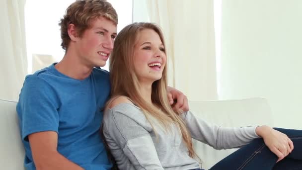 Sorrindo casal sentado no sofá com um controle remoto — Vídeo de Stock