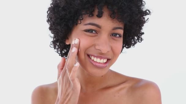 Mooie vrouw aanbrengen crème op haar gezicht — Stockvideo