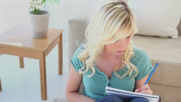 Junge blonde Frau schreibt in ein Notizbuch — Stockvideo