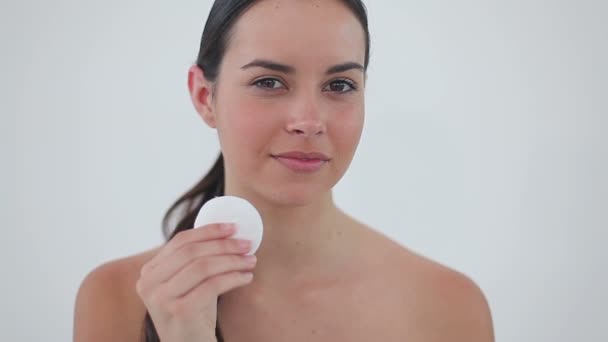 Mujer morena sonriente usando una compresa de algodón — Vídeos de Stock