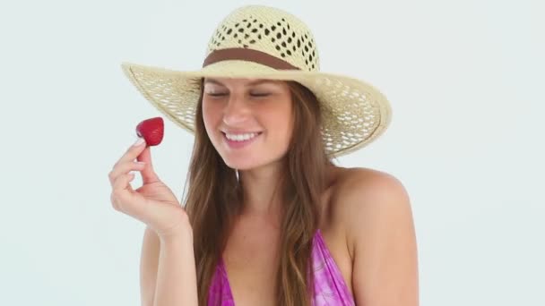 Mujer usando un sombrero de playa comiendo una fresa — Vídeo de stock