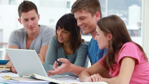 Estudiantes sonrientes usando un portátil juntos — Vídeo de stock