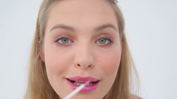 Blonde woman applying lip gloss on her lips — Stock Video