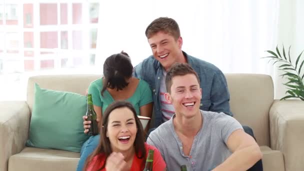 Teman-teman tersenyum melihat televisi sambil tertawa — Stok Video