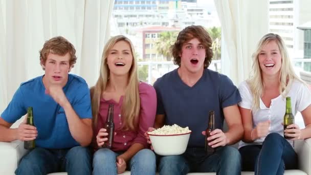 Happy friends eating popcorn while sitting — Stockvideo