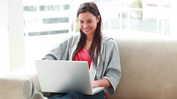 Lachende jonge vrouw met behulp van een laptop — Stockvideo