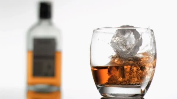 Ледяные кубики в замедленной съемке падают в стакан виски — стоковое видео