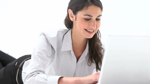 Woman lying on belly while using a laptop — Stock Video