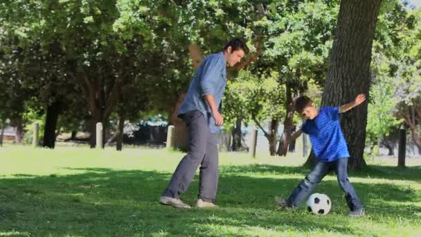 Сын и его отец играют в футбол — стоковое видео