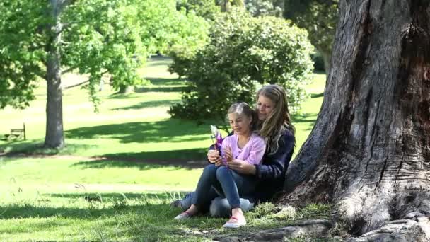 Mother and his daughter holding a pinwheel in a park — Stock Video