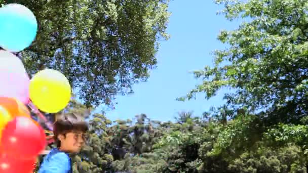 Хлопчик грає з гумовою кулею в парку — стокове відео