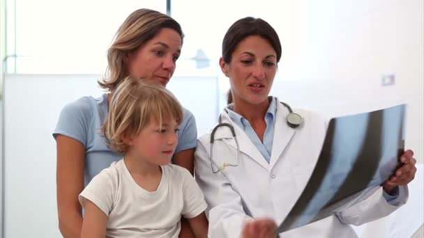 Médico examinando la radiografía junto a una madre y su hijo — Vídeo de stock