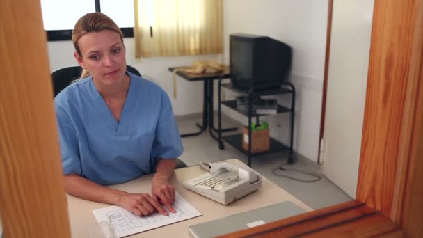 Nurse looking at files at a reception desk — Stock Video