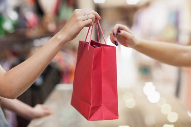 Woman handing over shopping bag clipart