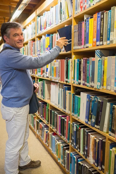 Hombre eligiendo libro de estante — Foto de Stock