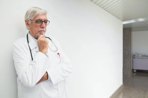 Doctor leaning against wall in corridor and thinking — Stock Photo, Image