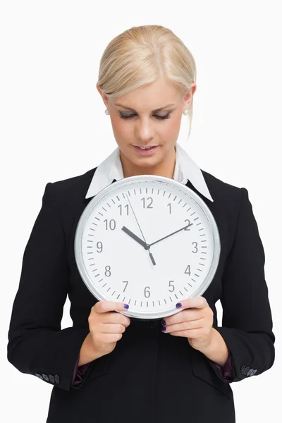 Smiling blonde in suit holding a clock — Stock Photo, Image