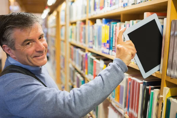 微笑考虑从书架上一台 tablet pc 的男人 — 图库照片