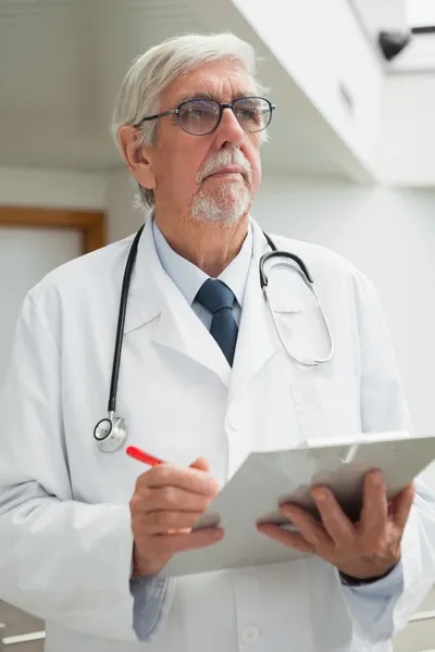 Doctor holding patient file and looking up — Stock Photo, Image
