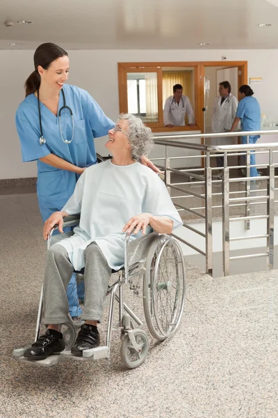 Enfermera sonriendo a ancianas sentadas en silla de ruedas — Foto de Stock