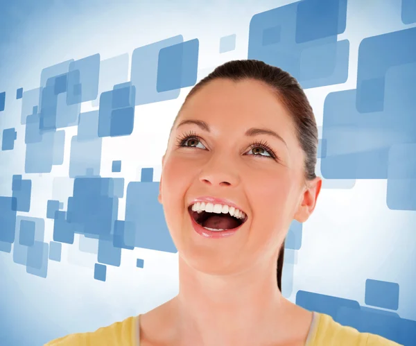 Woman looking up against blue background — Stock Photo, Image