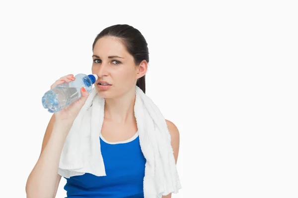 Sportswoman with a towel drinking water — Stock Photo, Image
