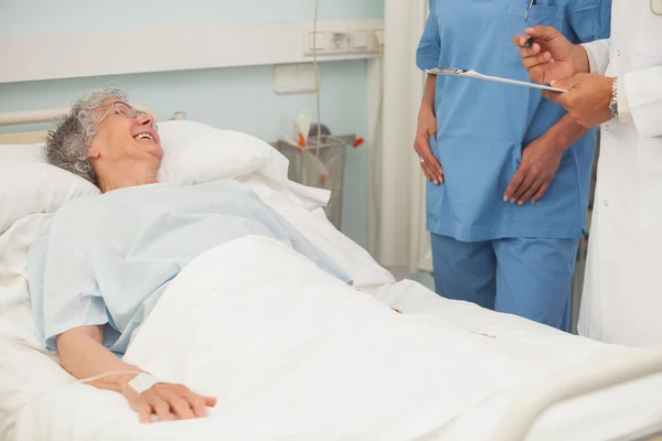 Paciente idosa do sexo feminino sorrindo para o enfermeiro e médico — Fotografia de Stock