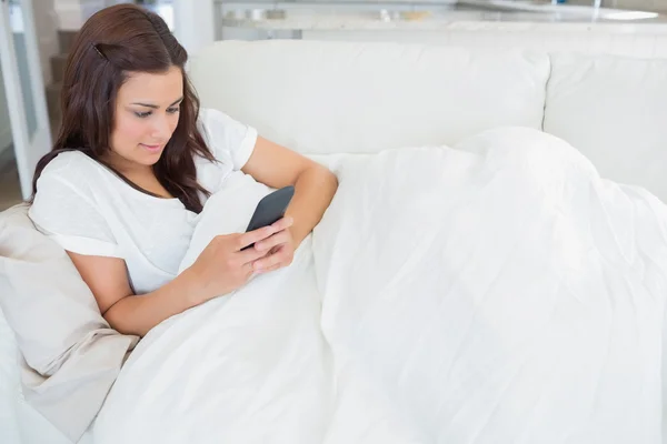 Frau beim SMS-Schreiben auf der Couch liegend — Stockfoto
