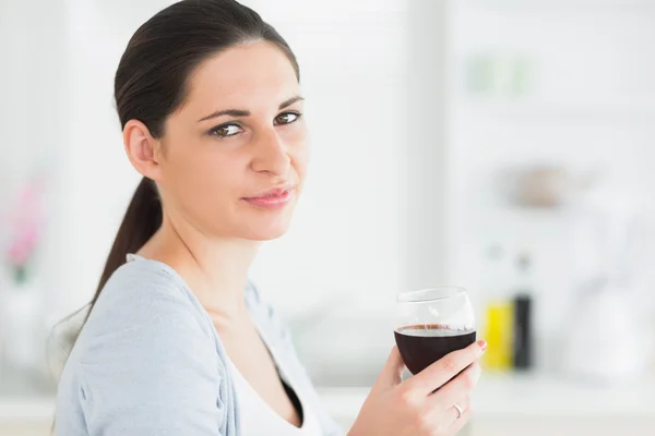 Mulher sorridente segurando copo de vinho tinto — Fotografia de Stock