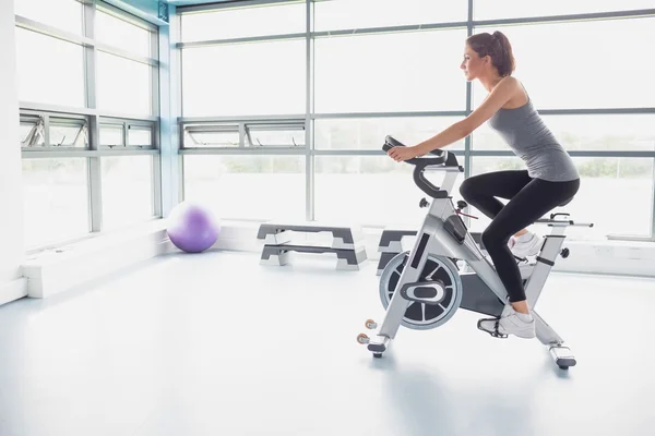 Woman riding an exercise bike — Stock Photo, Image
