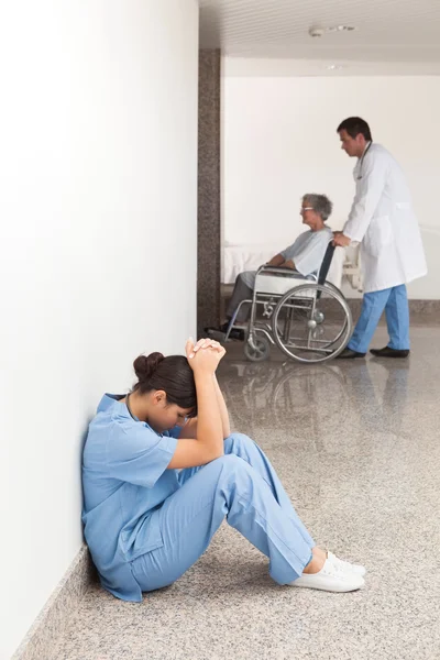 Nurse sitting in the hallway getting depressed — Stock Photo, Image