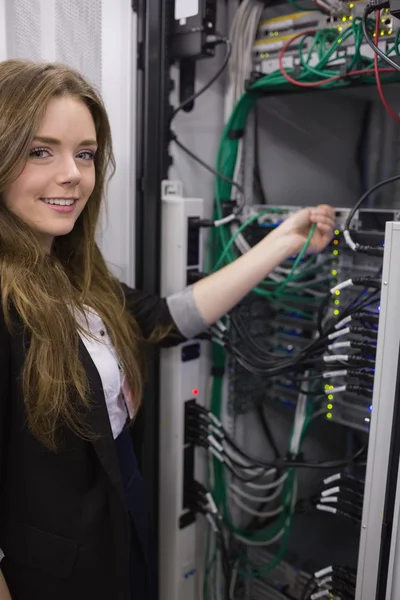 Menina sorrindo trabalhando em servidores montados em rack — Fotografia de Stock