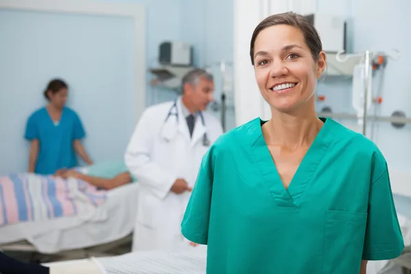 Verpleegkundige is permanent ziekenhuis kamer en glimlachen — Stockfoto