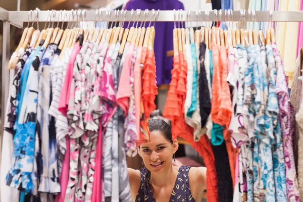 Mujer de pie detrás de un estante de ropa sonriendo — Foto de Stock