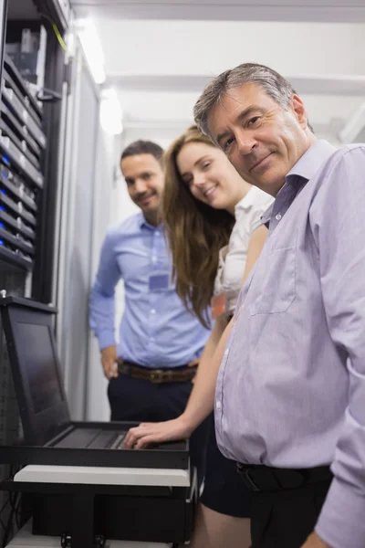 Three happy technicians checking servers with laptop — Stock Photo, Image