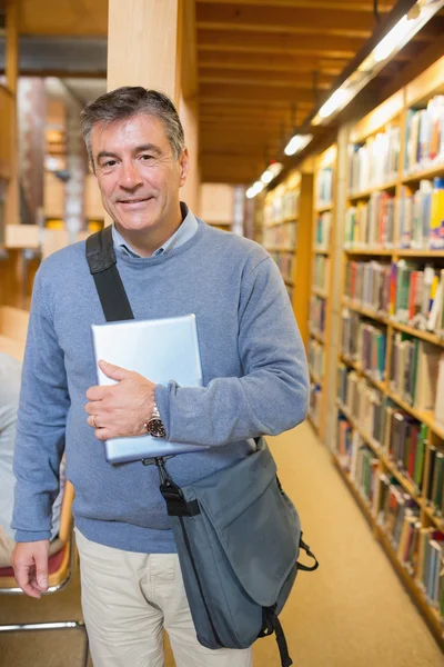Homem de pé ao lado de prateleiras em uma biblioteca — Fotografia de Stock