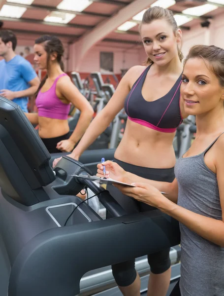 Happy woman and instructor in the gym — Stock Photo, Image