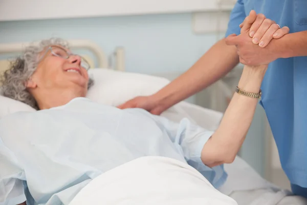 Пожилой пациент держит за руку медсестру — стоковое фото